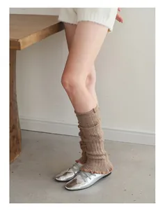 Detail of brown wool-blend leg warmers with scalloped edges and silver ballet flats