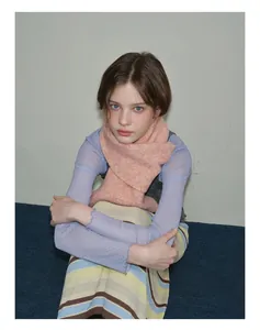 Gros plan d'une écharpe en laine rose orangé avec un haut violet à pois transparent