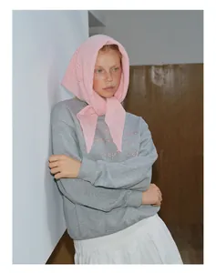 Vue détaillée du foulard en laine rose ajourée avec un sweat-shirt gris brodé