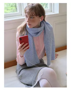 Detail of wool blend cable knit scarf styled with pink cardigan and grey skirt