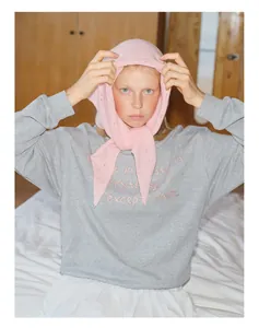 Détail d'une écharpe triangle rose en maille 100 % laine avec un sweat-shirt gris décontracté