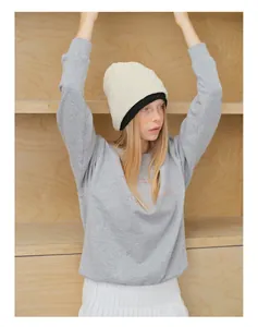Detailansicht der rosa Stickerei auf grauem Sweatshirt mit weißer Strickmütze