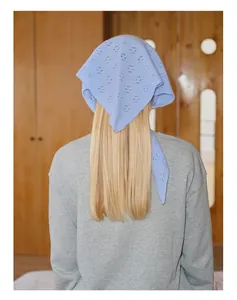 Détail du tricot de l'écharpe triangle en laine bleu clair sur cheveux blonds