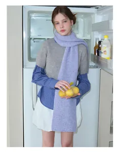 Detail view of a purple ribbed wool scarf paired with a grey sweater and white pleated skirt