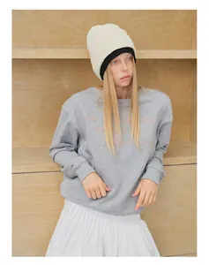 Detailaufnahme einer grauen Strickmütze kombiniert mit einem bestickten Sweatshirt