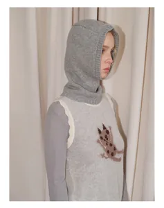 Detail der grauen Woll-Balaclava kombiniert mit einer Strickweste mit Katzenmuster