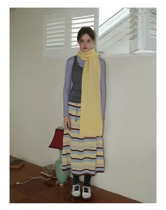 Détail d'une écharpe en laine jaune douce associée à une jupe en tricot vintage