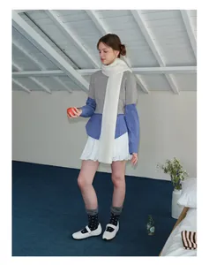 Winter outfit featuring a chunky white wool scarf with a grey knit vest and blue shirt