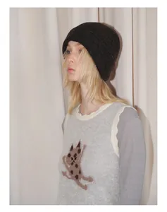 Detailed close-up of charcoal grey knitted beanie paired with a cat pattern vest