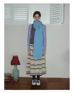 Look complet avec écharpe en maille bleu clair et gilet gris dans un studio rétro chic