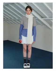 Detail of grey wool knit scarf paired with a blue checkered shirt and pleated skirt