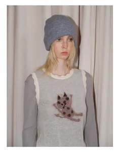 Detail view of light grey ribbed knit beanie and soft mohair vest with cat intarsia pattern