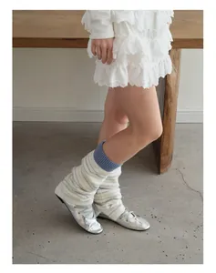 Close-up of striped wool blend leg warmers styled with silver ballet flats on wood bench