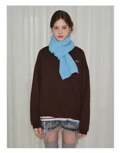 Detail of light blue knitted wool scarf styled with a brown sweatshirt and casual shorts