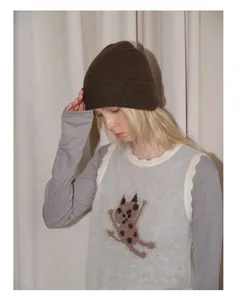 Detail view of dark brown yak wool knit beanie styled with a grey cat pattern vest