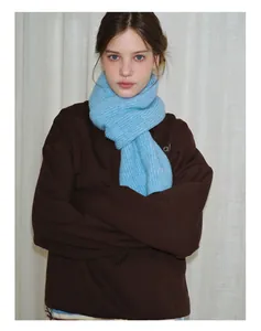 Detail of bright blue knitted wool scarf styled over a brown oversized sweatshirt