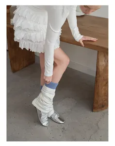 Detail of striped knitted leg warmers with sky blue ribbed cuffs and silver ballet flats