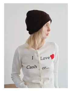 Detailansicht eines Modells mit weicher dunkelbrauner Strickmütze und weißem Slogan-Cardigan