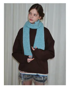 Detailed view of light blue knitted wool scarf with vertical ribbed texture and soft fringes