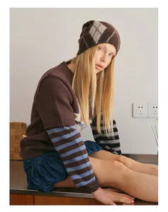 Detailed knit texture of a brown argyle wool blend beanie and matching striped sweater
