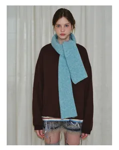 Detail view of thick light blue wool knit scarf paired with dark brown oversized sweater