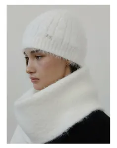 Close-up of white knitted wool scarf with metallic knot detail on soft plush fabric