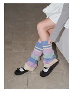 Detail of colorful striped wool knit leg warmers paired with black Mary Jane shoes