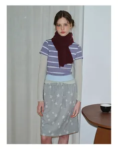 Détail d'une écharpe en tricot bordeaux avec t-shirt rayé et jupe à motif d'étoiles