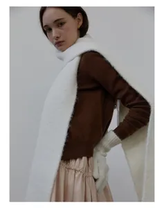 Detail showing plush white wool blend scarf paired with brown knit sweater and gloves