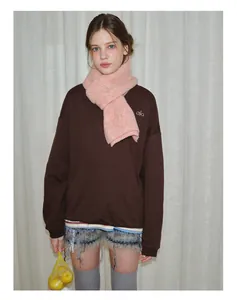Detail view of thick pink knit wool scarf layered over a brown sweatshirt