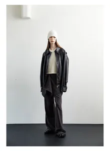 Full body look of a white wool knit beanie paired with a black faux leather jacket
