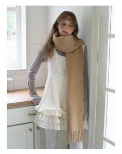 Detail of camel alpaca wool blend scarf featuring thick knit texture and long tassels