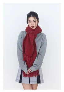 Detalle de una bufanda de lana roja con flecos llevada por una modelo con jersey gris