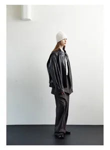 Profile shot of a black oversized leather jacket with zipper and minimalist styling