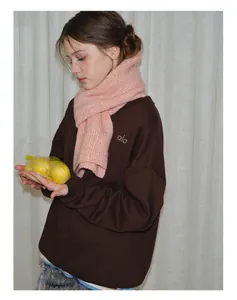 Detail of soft pink knitted wool scarf texture paired with a brown winter sweatshirt
