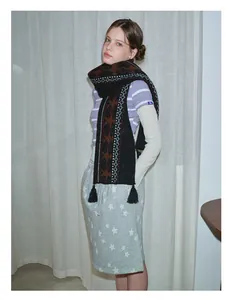 Close-up of Fair Isle knit scarf with geometric pattern and black tassels in wool blend
