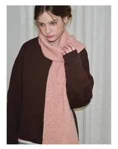 Detail of soft pink ribbed knit wool scarf paired with a brown sweatshirt on model