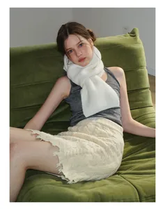Détail de l'écharpe en laine blanche douce avec gilet gris et jupe à franges en tricot