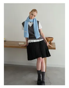 Detailansicht eines hellblauen Wollmischschals kombiniert mit grauer Strickweste und Bluse