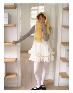 Full view of women winter outfit featuring a thick yellow tasseled alpaca wool scarf