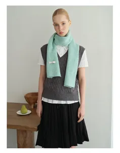 Winter-Outfit-Styling mit mintgrünem Grobstrickschal und schwarzem Faltenrock