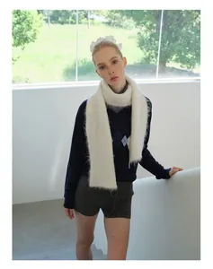 Witte alpaca wollen gebreide sjaal gestyled met een marine trui en grijze shorts