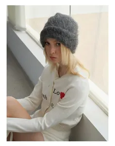Detail of gray alpaca knit beanie paired with a white cardigan and red heart embroidery