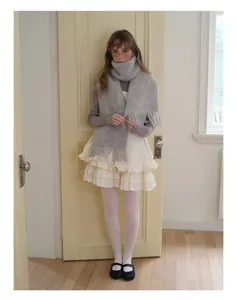 Detail of grey alpaca wool scarf with tassels paired with layered white ruffle dress