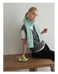 Detailaufnahme von hellgrünem Wollmischgewebe-Strickschal mit minimalistischem Markenetikett