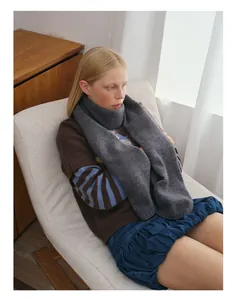 Detail der Textur des grauen Wollstrickschals und gemütliches Winter-Styling auf Sessel
