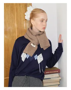 Detail eines weichen braunen Rippstrickschals aus Wollmischung mit weißem Textiletikett