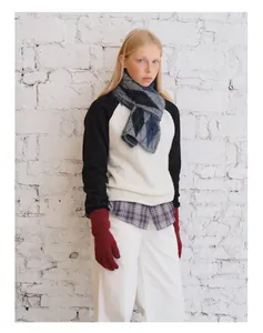 Detail eines Argyle-Wollmischschals mit weinroten Strickhandschuhen für den Winter