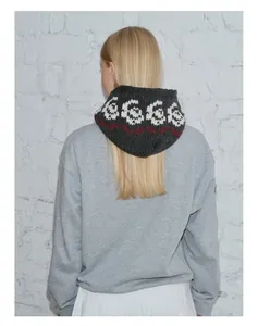 Detail view of dark grey knitted balaclava with white 6666 jacquard pattern and red accents