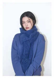 Detalle de bufanda suave de lana azul marino con flecos sobre una sudadera minimalista